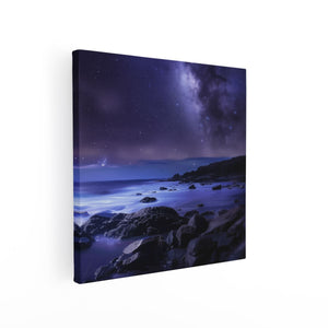 Canvas schilderij vierkant Nachtelijke Hemel met Sterren en een Rotsachtig Strand