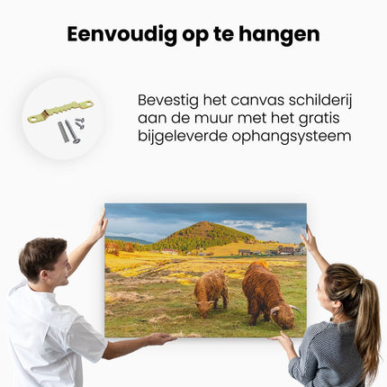 Canvas schilderij ophangen Twee Schotse Hooglanders bij een Dorp