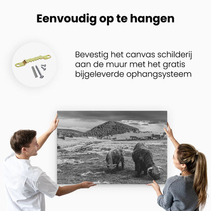 Canvas schilderij ophangen Twee Schotse Hooglanders bij een Dorp - Zwart Wit