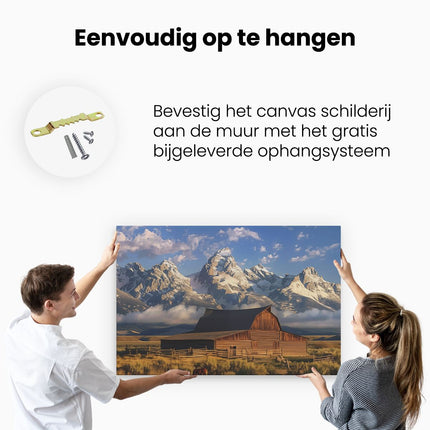 Canvas schilderij ophangen Schuur Midden in een Veld met Bergen op de Achtergrond